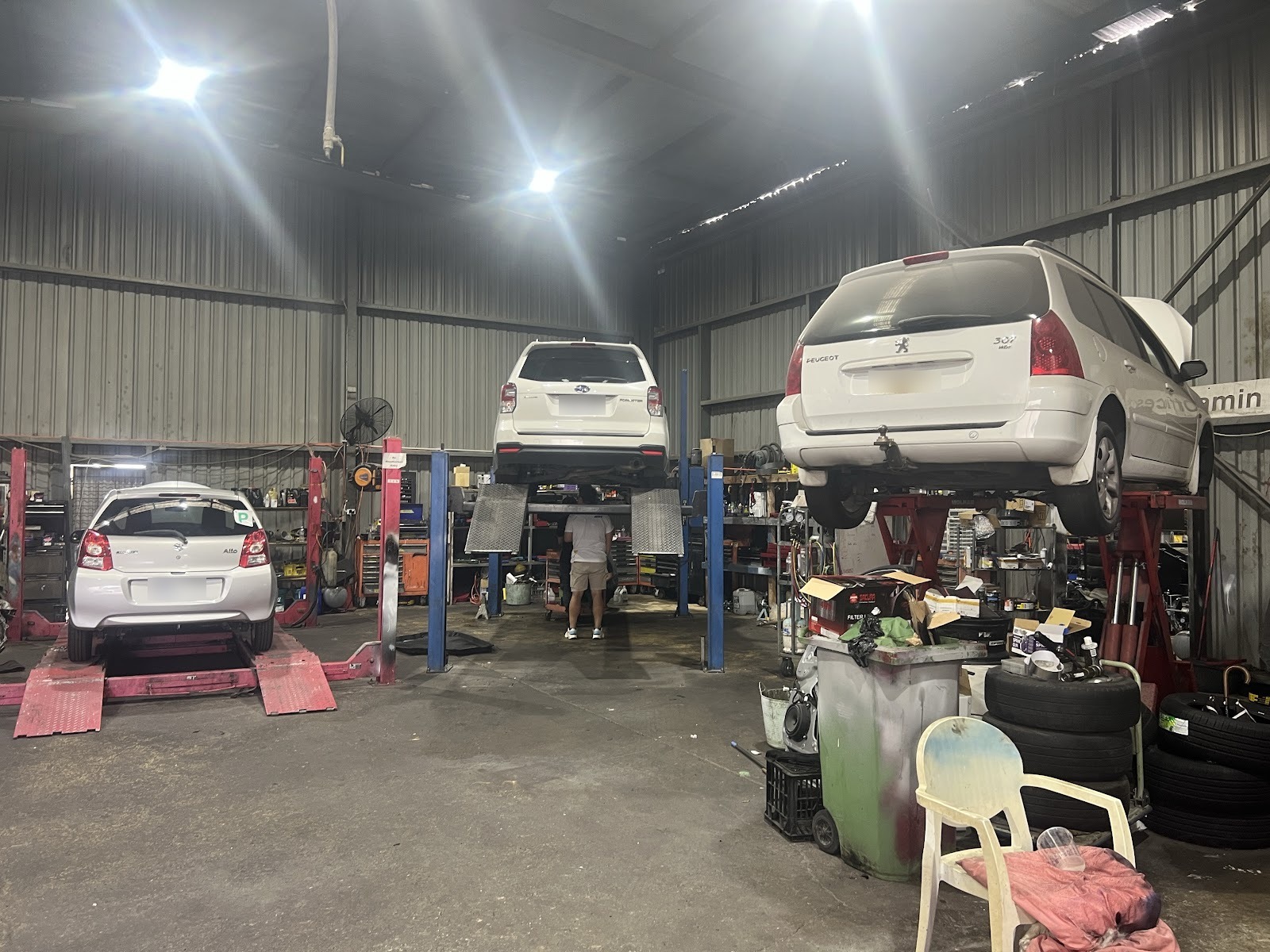 Inside the workshop: three cars up on hoists being worked on